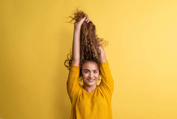 Portrait of a young woman in a studio on a yellow background, having fun. — Stock Photo, Image