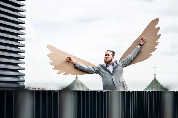 Ένας νέος επιχειρηματίας με φτερά που στέκονται σε μια βεράντα, που πετούν ιδέα μεταφορά. — Φωτογραφία Αρχείου