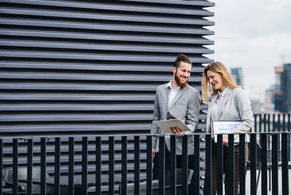 Zwei junge Geschäftsleute mit Tablet stehen auf einer Terrasse vor dem Büro und arbeiten. — Stockfoto