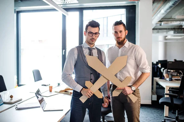 Dois jovens empresários com espadas em um escritório, se divertindo. Um conceito de concorrência . — Fotografia de Stock