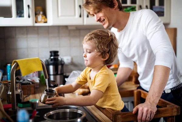 Młody ojciec z synem malucha w kuchni w domu. — Zdjęcie stockowe
