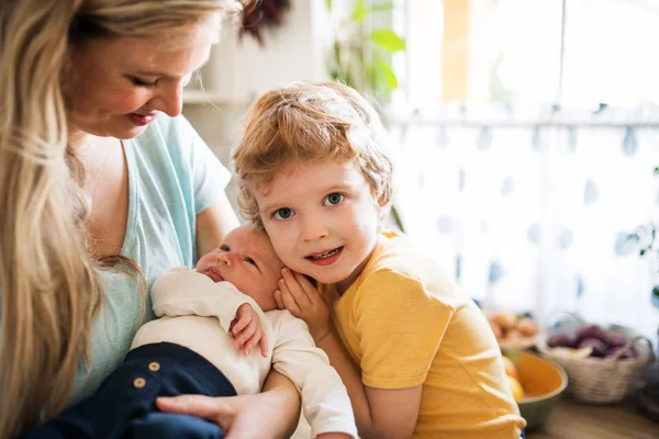 Μια όμορφη νεαρή μητέρα με ένα νεογέννητο μωρό και ο αδελφός του στο σπίτι. — Φωτογραφία Αρχείου