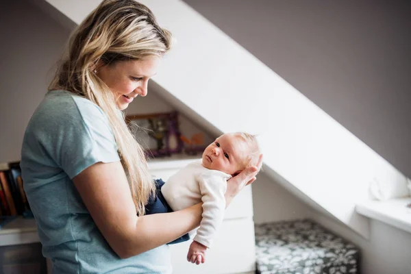 A beautiful young mother with a newborn baby at home. — Stock Photo, Image