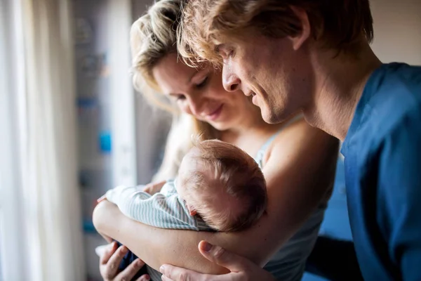 Hermosos padres jóvenes con un bebé recién nacido en casa . —  Fotos de Stock