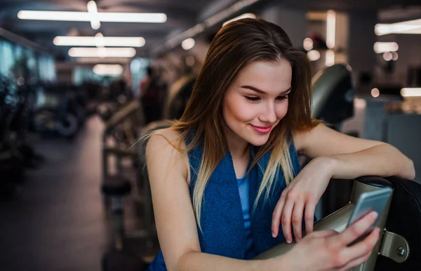 Ένα πορτρέτο του νεαρή κοπέλα ή γυναίκα με το smartphone σε ένα γυμναστήριο, λήψη selfie. — Φωτογραφία Αρχείου