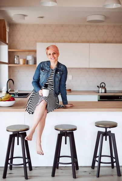 Bir sayaç bir mutfak evde oturan bir genç çekici kadın. — Stok fotoğraf