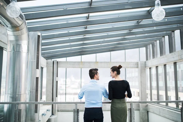 Bakifrån av unga företagare som står på kontoret, pratar. — Stockfoto