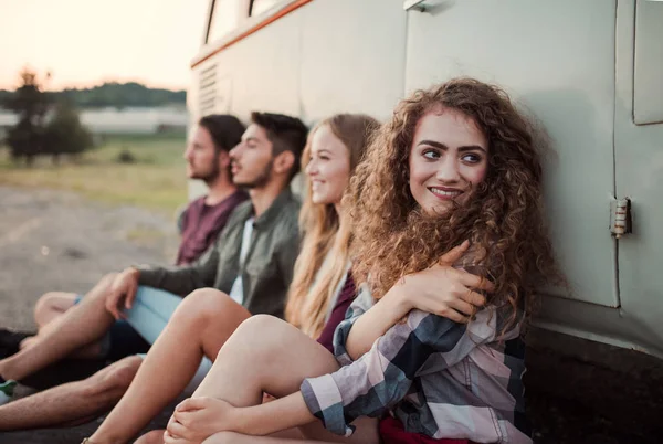 En grupp unga vänner på en roadtrip genom landsbygden, sitter av en minibuss. — Stockfoto