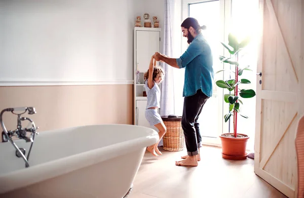 Klein meisje met jonge vader in de badkamer thuis, plezier. — Stockfoto