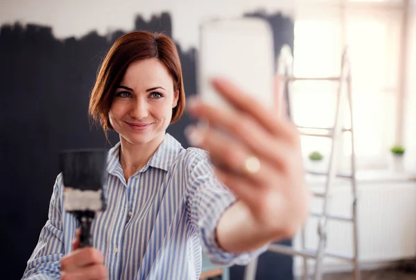 Portret młodej kobiety malowanie ścian czarny, biorąc selfie. — Zdjęcie stockowe