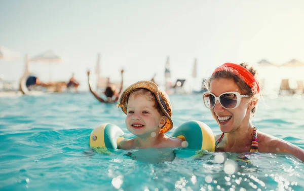 Un piccolo bambino con bracciali e mamma che nuota in acqua durante le vacanze estive . — Foto Stock
