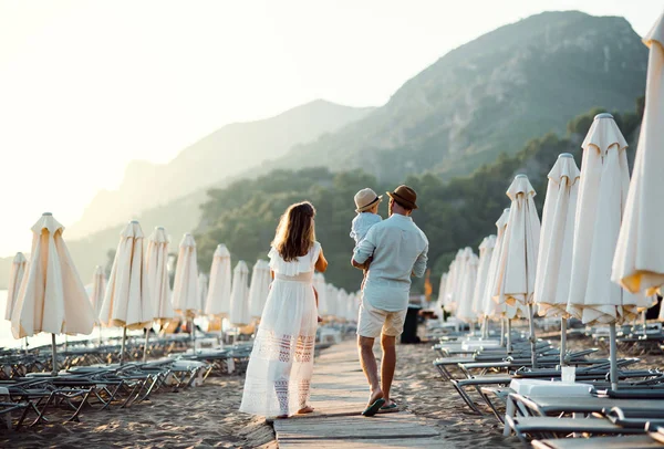 Vista trasera de la familia con dos niños pequeños caminando en la playa en vacaciones de verano . — Foto de Stock