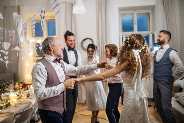 Una novia joven bailando con el abuelo y otros invitados en una recepción de boda . — Foto de Stock