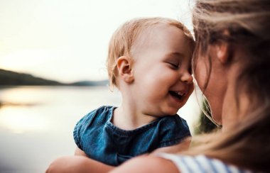 Anne açık havada yaz aylarında nehir kıyısında yürümeye başlayan çocuk kızı olan bir close-up.