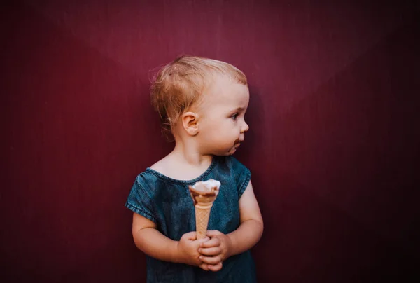 Une vue de face de petite fille en plein air en été, manger de la crème glacée . — Photo