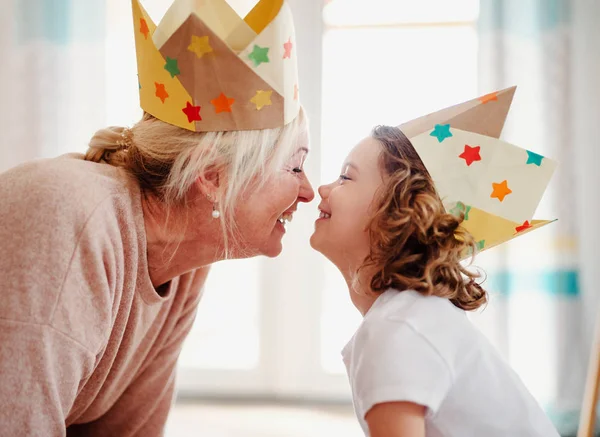 A portrait of small girl with grandmother at home, having fun. — Stock Photo, Image