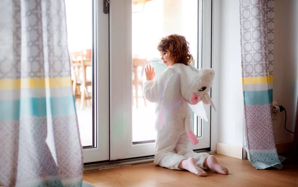 Una niña pequeña con máscara de unicornio jugando en casa . — Foto de Stock