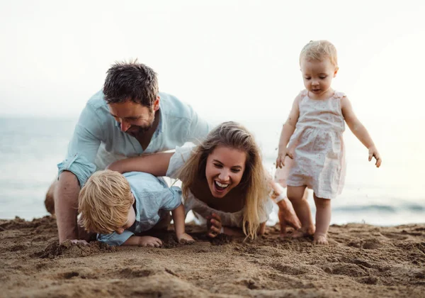 Young family with toddler children playing with sand on beach on summer holiday. — Stock Photo, Image