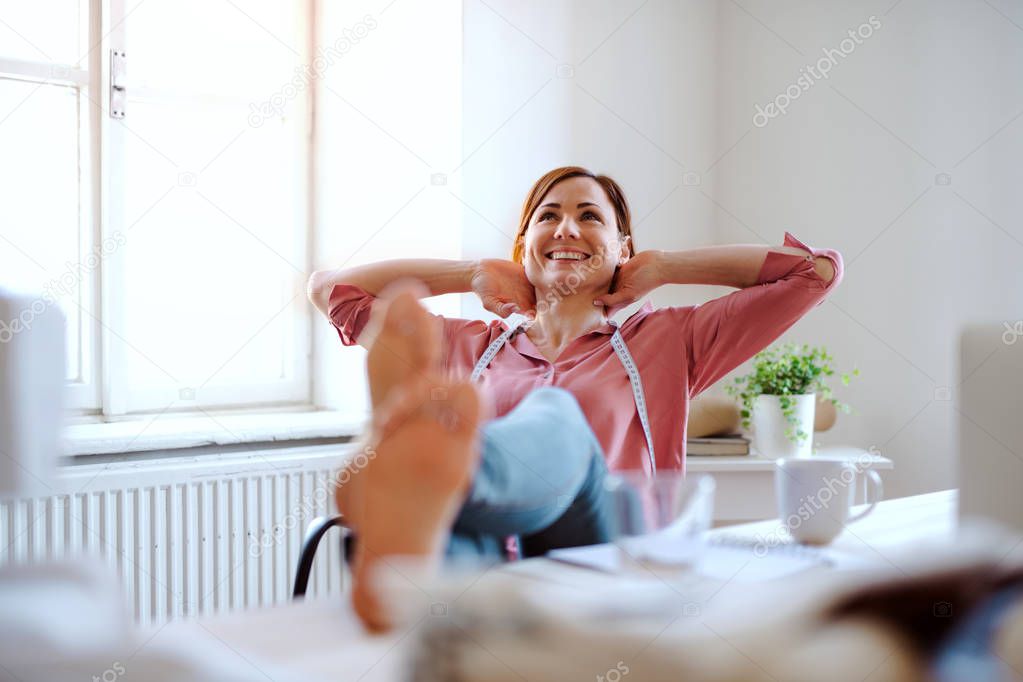 Young creative woman in a studio, resting. A startup of tailoring business.