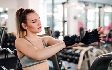 Genç kız ya da kadın spor salonunda eldiven takıyor..
