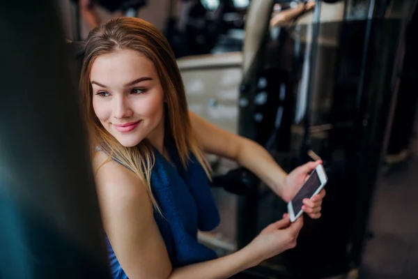 Bir spor salonunda akıllı telefon ile genç kız veya kadın bir portre. — Stok fotoğraf