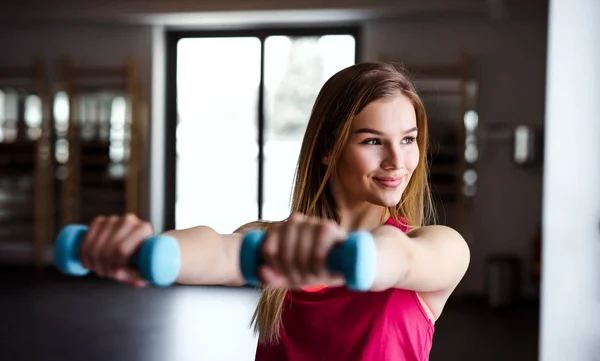 Genç kız ya da bir spor salonunda dumbbells ile egzersiz yaparak kadın portresi. — Stok fotoğraf