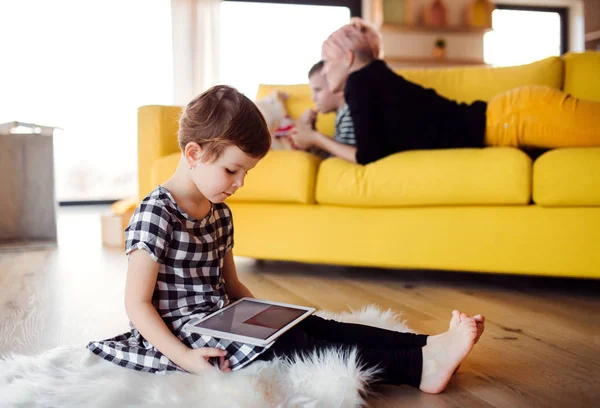 Ein kleines Mädchen mit Tablette zu Hause auf dem Fußboden. — Stockfoto