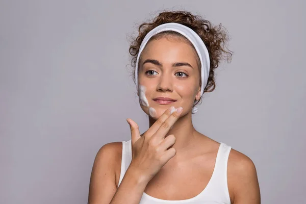 Portret van een jonge vrouw reinigen gezicht in een studio, schoonheid en huidverzorging. — Stockfoto