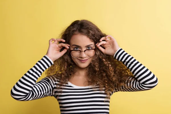 Πορτρέτο μιας νεαρής γυναίκας με γυαλιά σε ένα στούντιο σε κίτρινο φόντο. — Φωτογραφία Αρχείου