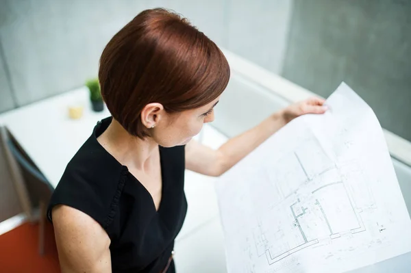 Ung affärskvinna eller arkitekt med ritningar som står i office. — Stockfoto