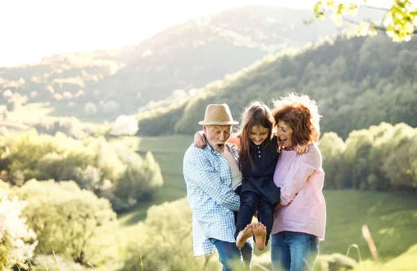 Seniorenpaar mit Enkelin im Frühling draußen in der Natur, entspannen und Spaß haben. — Stockfoto