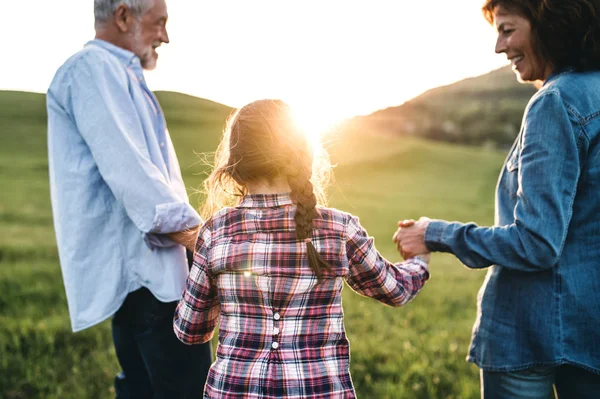 Vista posteriore di coppia anziana con nipote in una passeggiata fuori al tramonto . — Foto Stock