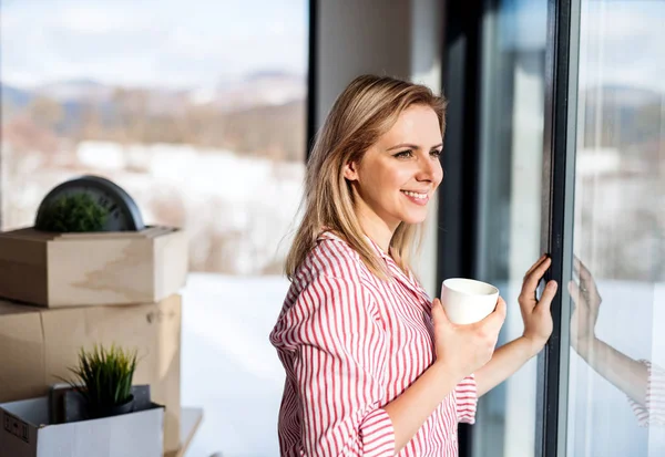 Eine junge Frau zieht in ihr neues Zuhause und trinkt Kaffee. — Stockfoto