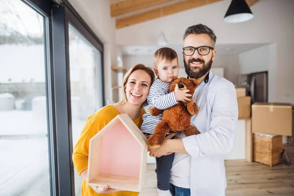 A portrait of young family with a toddler girl moving in new home. — Stock Photo, Image