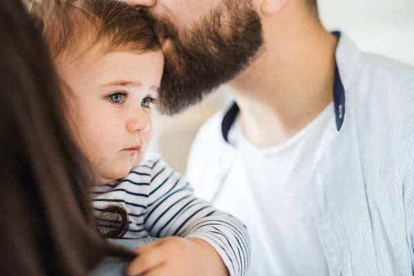 Sección media de la familia joven con la niña pequeña de pie en el interior de casa . — Foto de Stock