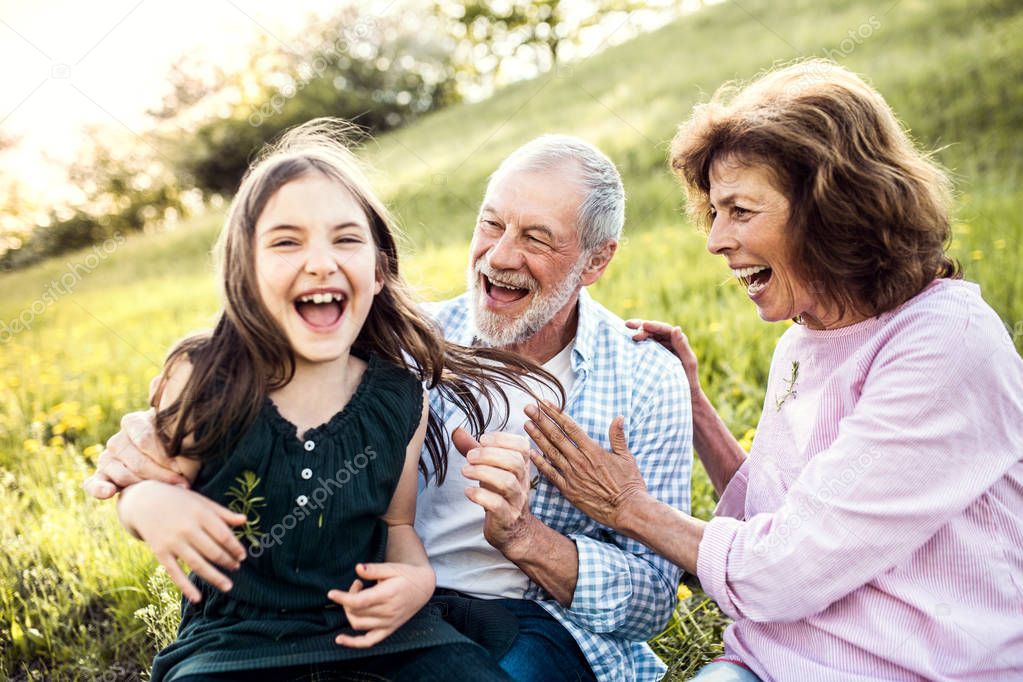 Senior couple with granddaughter outside in spring nature, having fun.