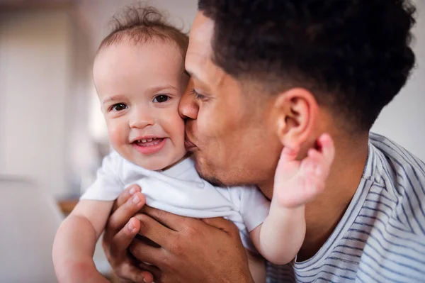 Un ritratto di padre e piccolo figlio bambino in casa, baciare . — Foto Stock