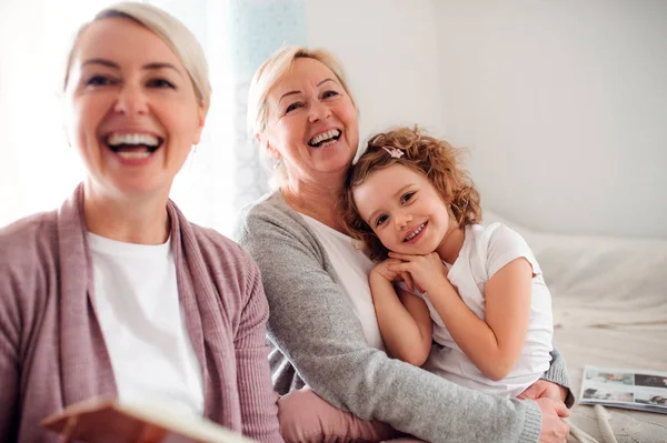 Una niña pequeña con madre y abuela en casa, riendo . — Foto de Stock