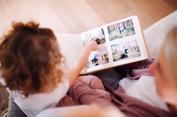 A small girl with mother and grandmother at home, looking at photographs. — Stock Photo, Image