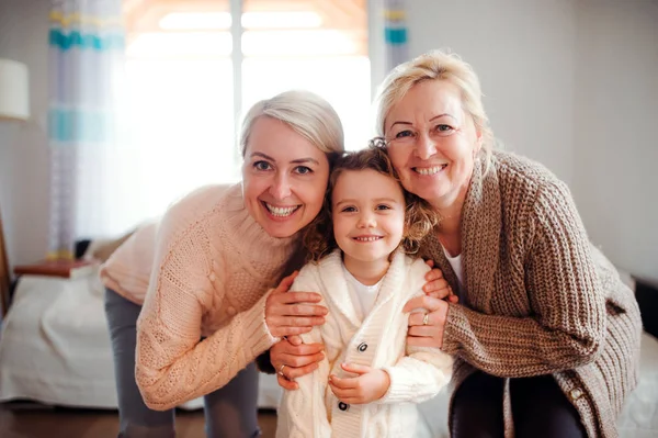 Ett porträtt av liten flicka med mor och mormor hemma. — Stockfoto