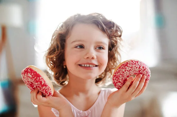 Маленькая девочка с пончиками дома, веселится . — стоковое фото