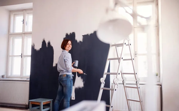 Um retrato de uma jovem mulher pintando parede preta. Uma startup de pequenas empresas . — Fotografia de Stock