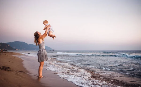 Giovane madre con una bambina sulla spiaggia in vacanza estiva. Copia spazio . — Foto Stock