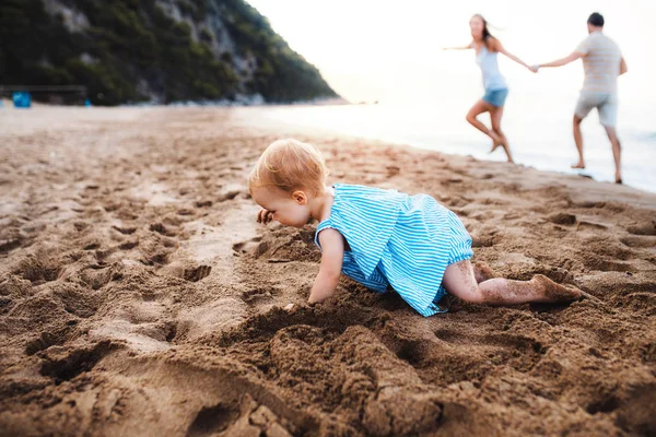 Una pequeña niña jugando en la arena en la playa en las vacaciones de verano . — Foto de Stock
