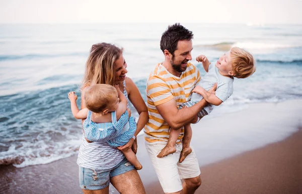 여름 휴가 해변에서 산책 두 유아 아이 들과 젊은 가족. — 스톡 사진