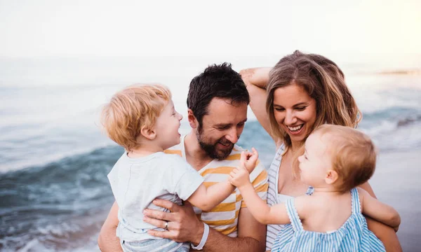 Jonge familie met twee peuter kinderen wandelen op het strand op zomervakantie. — Stockfoto