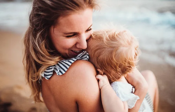 Primer plano de la madre joven con una niña en la playa en las vacaciones de verano . — Foto de Stock