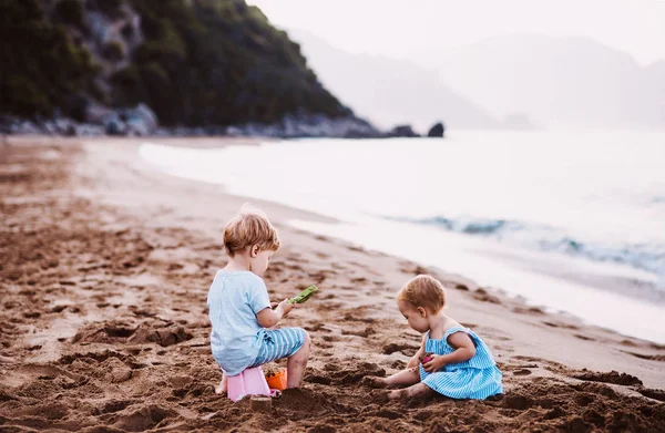 Dua anak kecil bermain di pantai pasir saat liburan musim panas . — Stok Foto