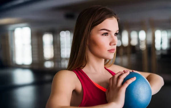 Портрет молодой девушки или женщины, делающей упражнения с мячом в спортзале . — стоковое фото