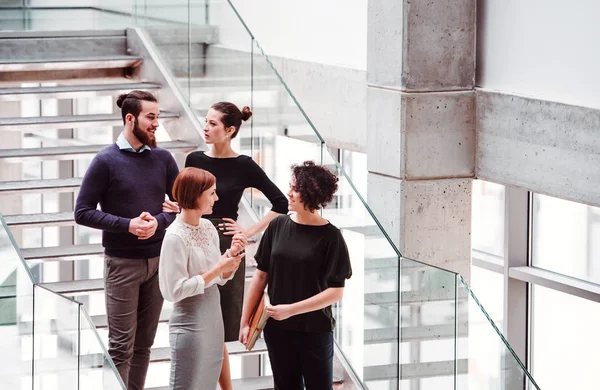 Gruppe junger Geschäftsleute steht in der Nähe der Treppe und redet. — Stockfoto